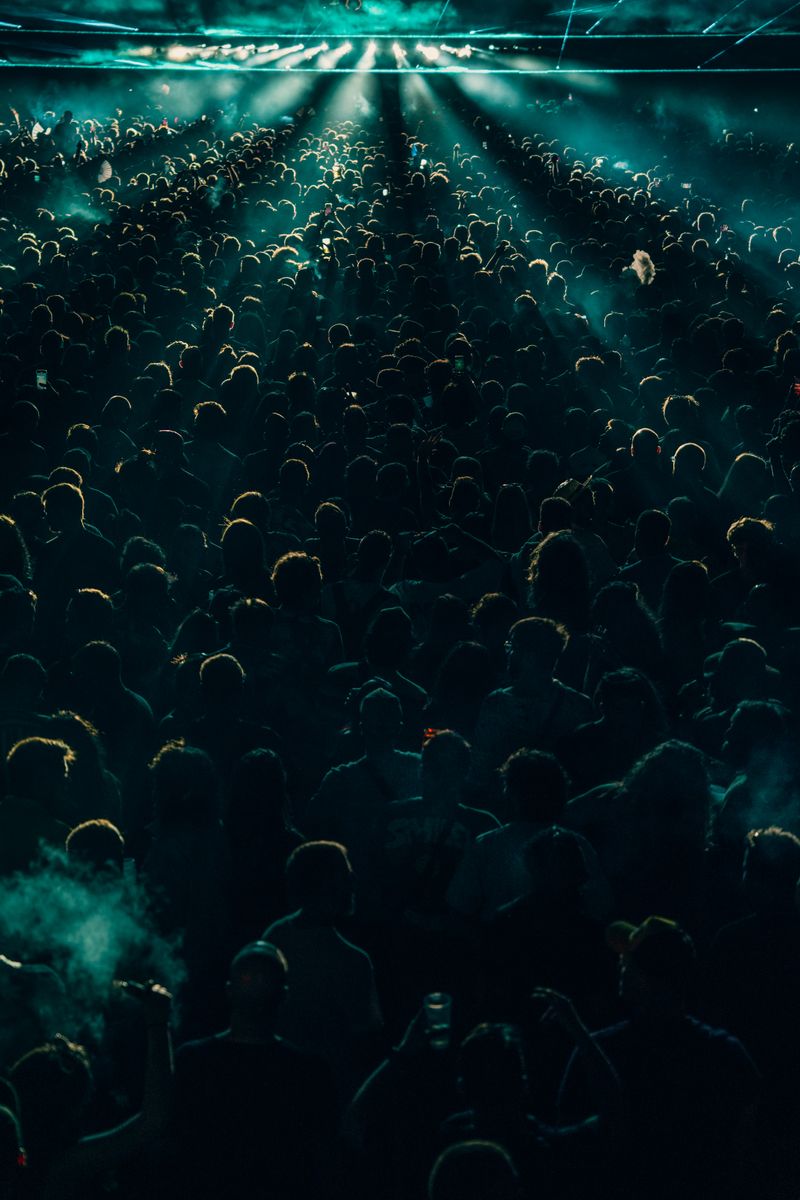 A crowd silhouetted under cool blue and teal stage lights