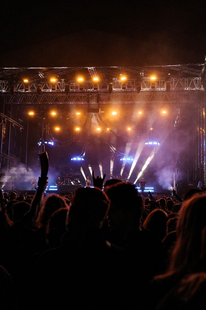 A concert crowd raising hands under warm stage lighting