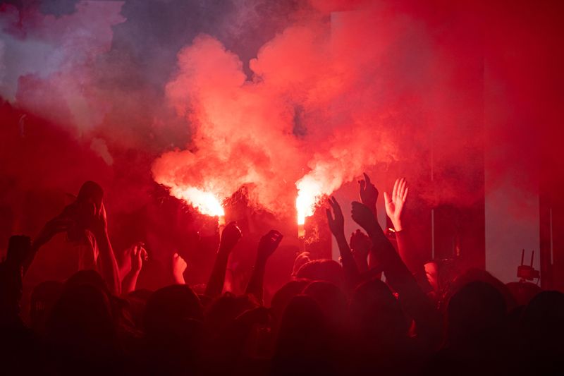 Red flares raised by hands in a night crowd