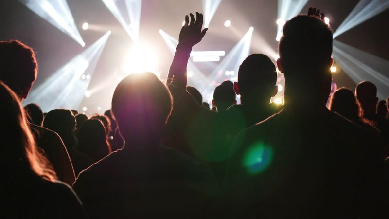 A crowd silhouetted against bright stage lights